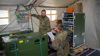 KomSys während Überprüfung von Steckverbindungen Hauptfeldwebel H. prüft gemeinsam mit einem Soldaten, in einem Zeltaufbau die zuvor installierten Verbindungswege der Kabel