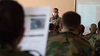 Afghanische Soldaten sitzen in einem Unterrichtsraum, vorne ein Dozent und eine Leinwand 