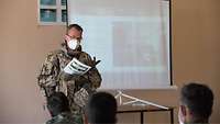 Ein deutscher Soldat steht neben einer Leinwand, auf die etwas projiziert wird