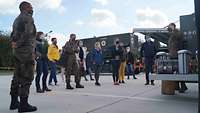 Die Teilnehmenden stehen vor der Mobilen Sauerstofferzeugungsanlage. Ein Soldat erklärt die Anlage.