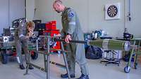 Überprüfung der Bordkanone durch zwei Mechaniker. Vor der Kanone stehen silberne Prüfpatronen.