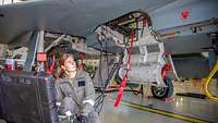Eine Waffenmechanikerin überprüft vor einem Eurofighter mithilfe einer schwarzen Box die Elektronik der Bordkanone