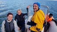 Zwei Frauen und ein Kind sitzen auf einem Boot und lassen sich von einem Mann über das Wasser fahren.