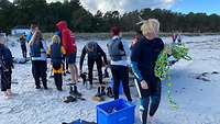 Die Betreuer und die Kinder stehen gesammelt am Strand und warten auf das Boot.