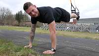 Ein Soldat macht Sport mit einem TRX-Band.