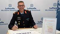 Generalmajor Ohl, Chef des Stabes im Kommando Luftwaffe, unterschreibt den Scheck über 1.020 Euro