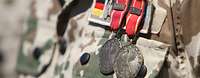 Zwei Einsatzmedaillen der Bundeswehr in Bronze sind an einem Feldanzug angesteckt.
