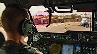 Ein Pilot sitzt im Cockpit hinter dem Steuer und schaut aufs Flugfeld vor ihm.