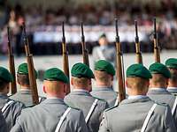 Feierliches Gelöbnis auf dem Paradeplatz des Bundesministeriums der Verteidigung in Berlin Mehrere Soldaten (von hinten gesehen) mit grünem Barett stehen mit ihren Gewehren in drei Reihen nebeneinander