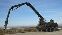 A tank with a long grip arm standing on a concrete surface