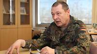 Dr. Kindling sitting at a table wearing a camouflage print uniform