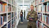 Ein Soldat steht in einer Bibliothek und lacht in die Kamera.