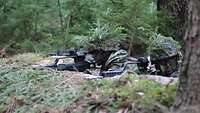 Zwei gut getarnte Soldaten liegen mit ihren Gewehren in einer Stellung im Wald. 