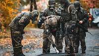 Mehrere Soldaten reinigen sich, ihre Waffen und Ausrüstung in mehreren auf den Boden gestellten schwarzen Wannen.