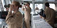 Soldaten der Bundeswehr stehen auf der Brücke eines Schiffes und schauen durch Ferngläser