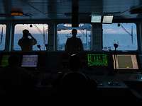 Bundeswehrsoldaten auf der Schiffsbrücke bei der Überwachung des Seeraums Soldaten der Bundeswehr in Rückenansicht stehen auf der Brücke eines Schiffes bei Dämmerung und schauen auf das offene Meer