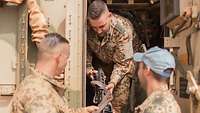 Drei Soldaten halten ein Maschinengewehr