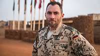 Ein Soldat im Portrait vor vielen verschiedenen Flaggen