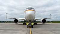 Der Airbus A350-900 steht in Parkposition auf einem Rollfeld. Zwei Mitarbeiter der Lufthansa arbeiten am Fahrwerk des Airbus.