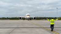 Das Regierungsflugzeug Airbus A350-900 fährt frontal auf einen Boden-Lotse zu.