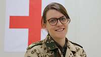 Eine Soldatin im Portrait. Hinter ihr ist das Sanitätskreuz an der Wand zu erkennen