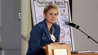 Dr. Yvonne Zimmermann bei ihrem Vortrag: Vor ihr steht ein Mikrofon, hinter ihr ein Flipchart von der Projektgruppe Personal