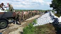 Soldaten beim Sandsackschleppen