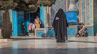 Im Vorhof der Moschee befinden sich Kinder, Frauen und ein älterer Herr sitzt in der Ecke mit einem Buch