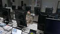 Ein Soldat sitz vor einem Computer, die anderen Plätze sind leer