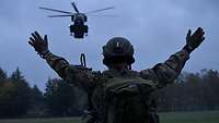 Ein Soldat weist einen Hubschrauber ein. 