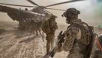 Soldaten gehen in Reihe auf einen Hubschrauber zu 