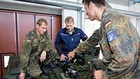 Zwei Soldaten und ein Zivilist reparieren und warten Fahrzeuge