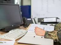 Unterlagen-Check: Auch Soldaten zahlen Steuern. Ein Bundeswehrsoldat sitzt an einem Schreibtisch vor einem aufgeschlagenen Ordner