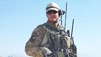 Ein Soldat mit Helm, Sprechsatz und Sonnenbrille schaut lächelnd in die Kamera.