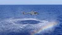 Ein Hubschrauber fliegt dicht über dem Wasser 