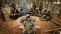 Soldaten sitzen zusammen im Gespräch in einem Wald
