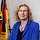 Eine blonde Frau sitzt vor der Bundesdienstflagge