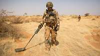 Ein deutscher Soldat sucht mit einem Minensuchgerät die Steppe in Mali ab