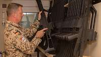 Ein Soldat nimmt eine Waffe aus einem Regal