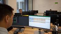 Drei Soldaten arbeiten an Computern in einem Hörsaal.