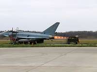 Triebwerkstestlauf eines Eurofighter Der Eurofighter steht am Boden und ist verankert. Aus dem Triebwerk kommt ein Hitzekegel.