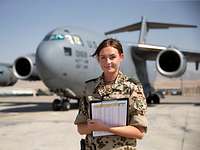 Eine Flugplanerin steht auf dem Rollfeld vor einer Boing C-17 bei der Mission Resolute Support.