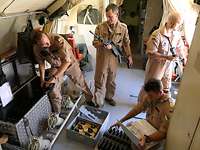 Vier Männer im inneren des Flugzeugs beladen eine Kiste mit Waffen und Munition