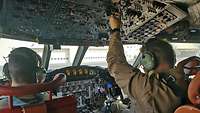 Zwei Männer sitzen angeschnallt im Cockpit und schauen auf die Instrumente