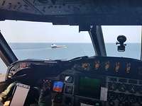 P-3C im Tiefflug über dem Wasser und nähert sich einem Schiff