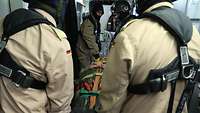 In einem Übungsszenario heben vier Soldaten eine Trage an, auf der Trage liegt ein Patient