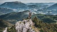 Drei Soldaten sitzen und stehen auf einem kleinen Felsen, dahinter das Panorama der Berchtesgadener Alpen.