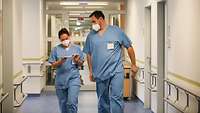Eine Soldatin und ein Soldat in Klinikkleidung auf dem Gang einer Station im Krankenhaus