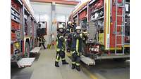 Markus Brechlin, Pascal Gilgenberger und Matthias Dieler in Feuerwehrmontur an einem Fahrzeug der Bundeswehrfeuerwehr.