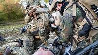 Zwei Soldaten legen bei einem Schwerstverwundeten ein Tourniquet an